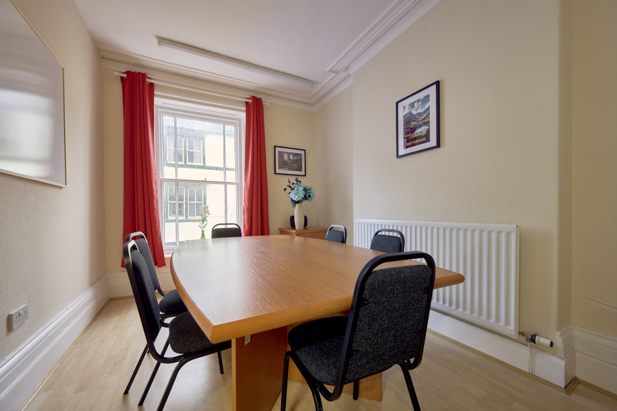 Meeting room at The Vicky — boardroom table for 6 with red curtains